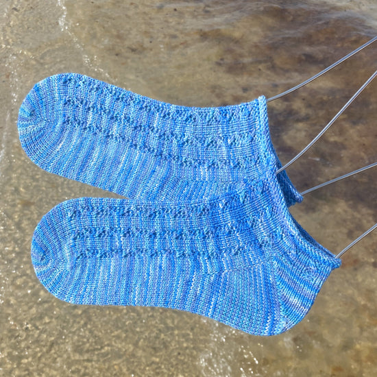 blue variegated ankle socks with wave cables with beach in the background