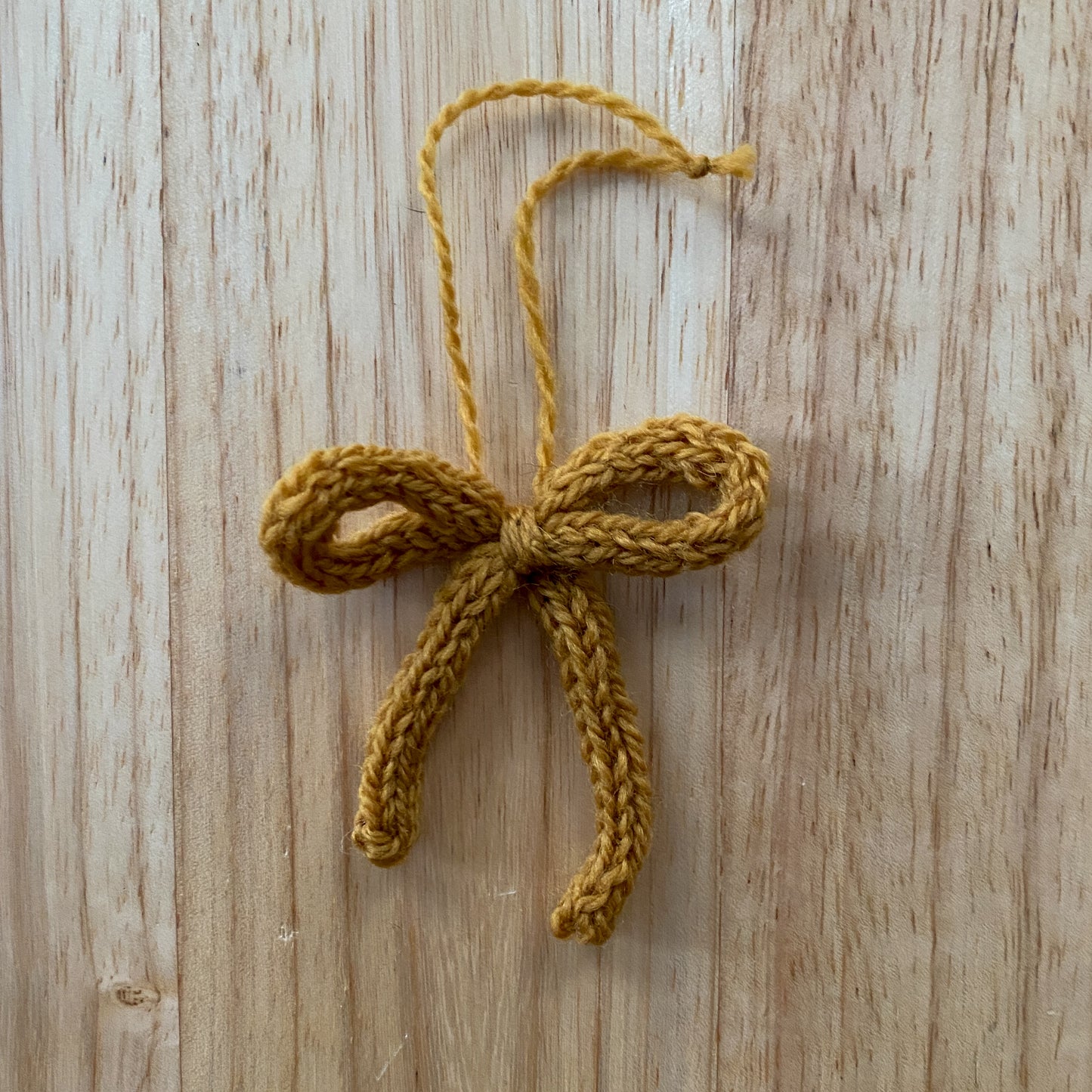 Knitted yellow bow ornament on a wooden surface