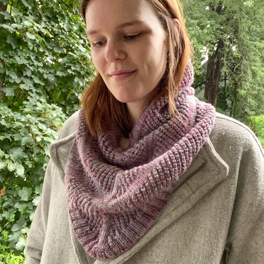 jules, the designer, wearing a lace striped cowl with ribbing in a purple/pink yarn
