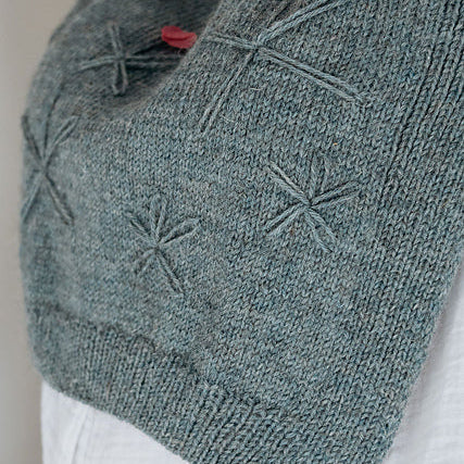 Gray knitted vest with embroidered patterns on a neutral background