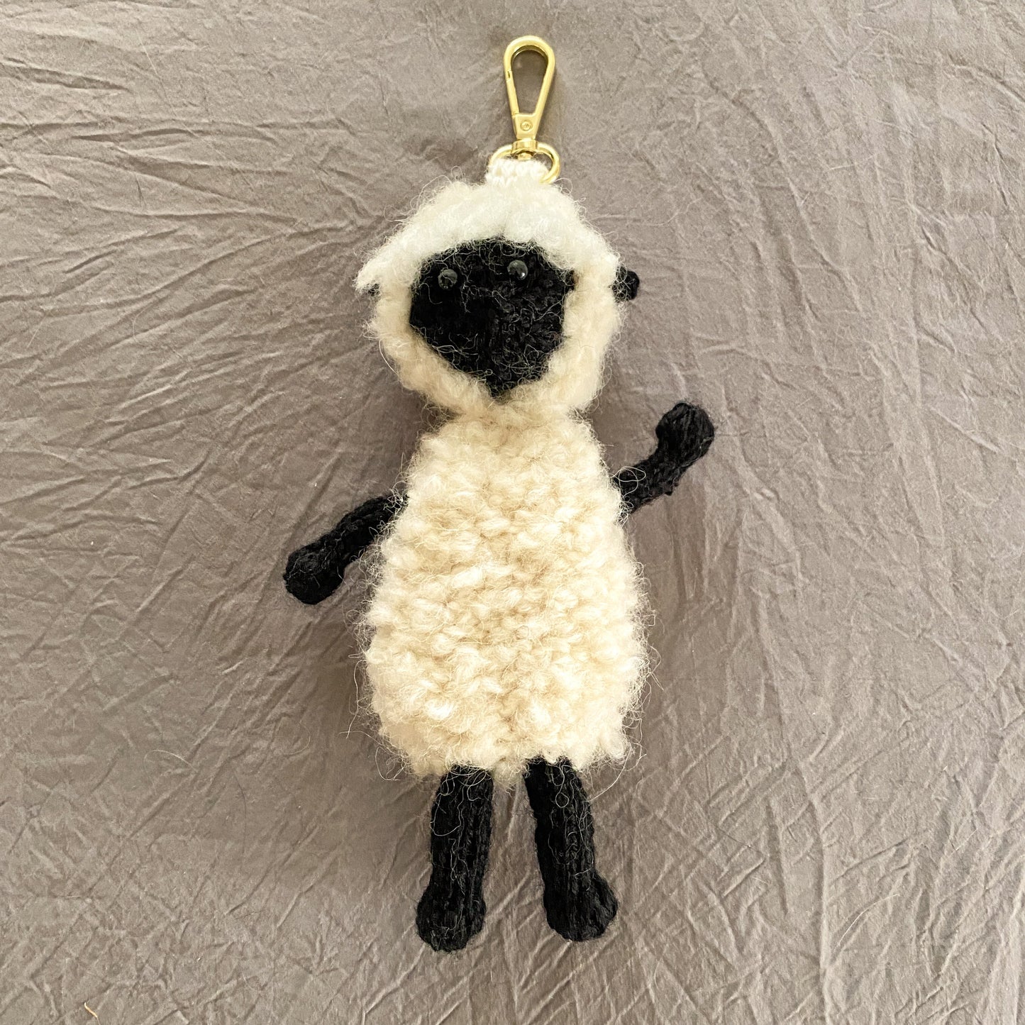 Sheep-shaped keychain on a textured gray background