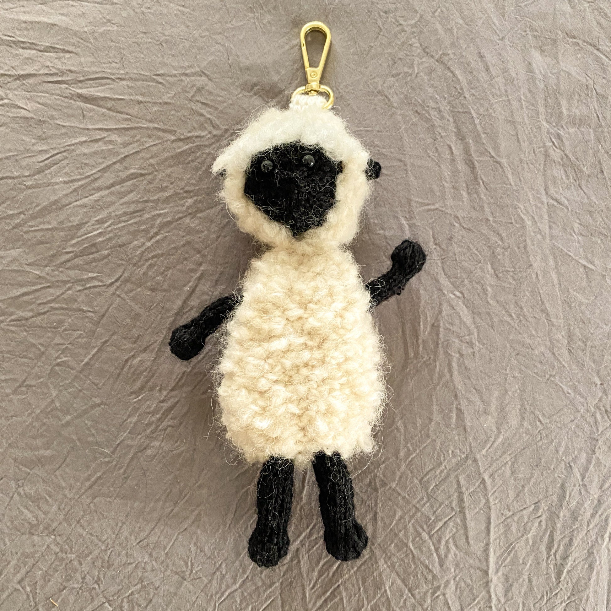 Sheep-shaped keychain on a textured gray background