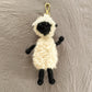 Sheep-shaped keychain on a textured gray background
