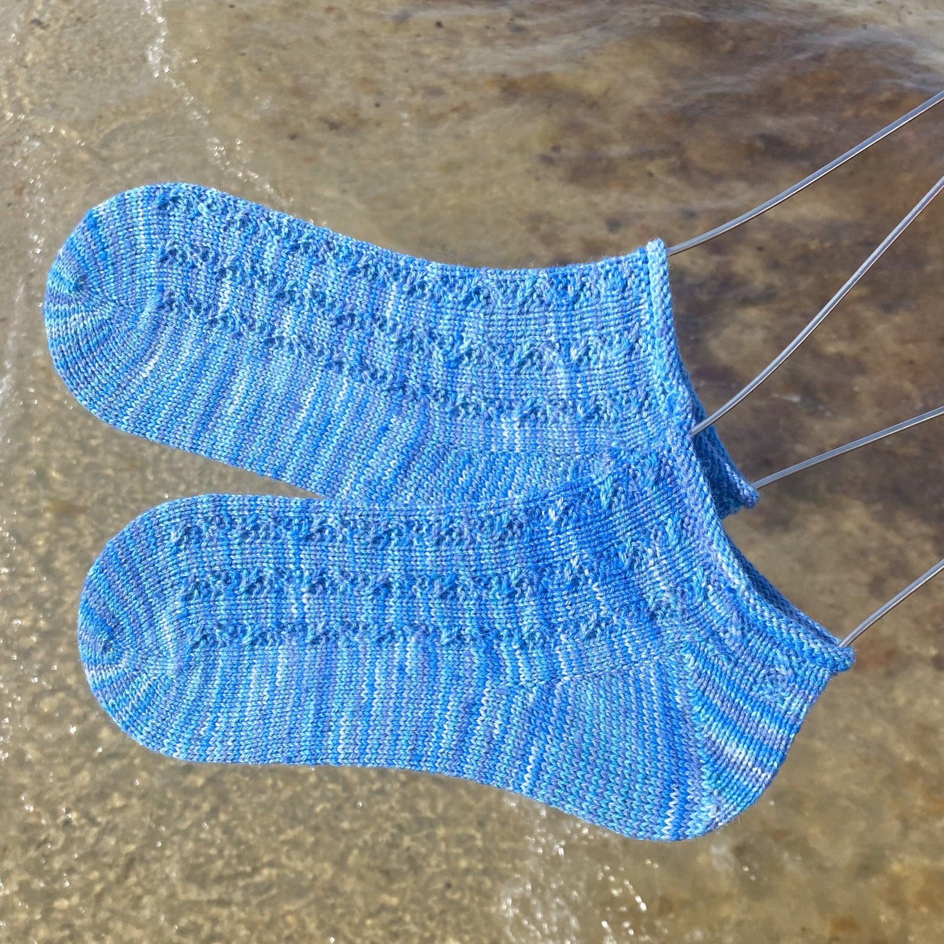 blue variegated ankle socks with wave cables with beach in the background