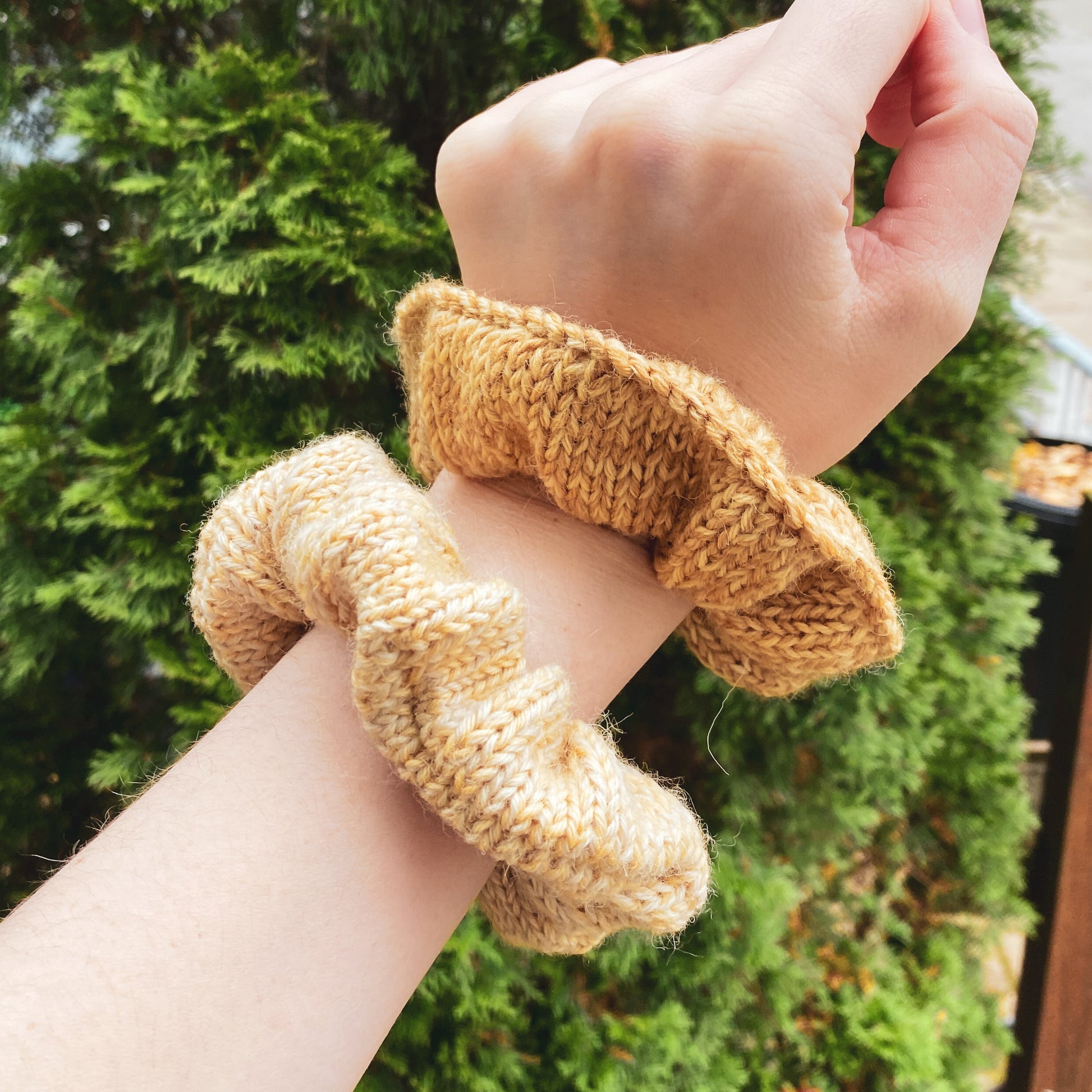 two knitted scrunchies on a white woman's wrist