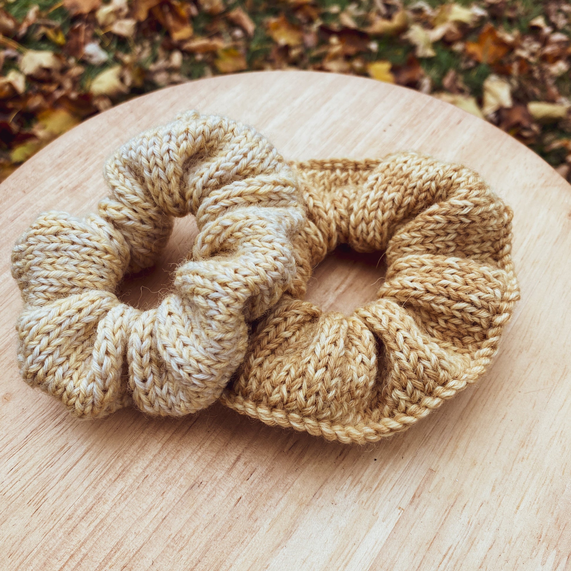 two knitted scrunchies on a wooden surface with a natural background