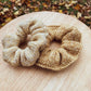 two knitted scrunchies on a wooden surface with a natural background