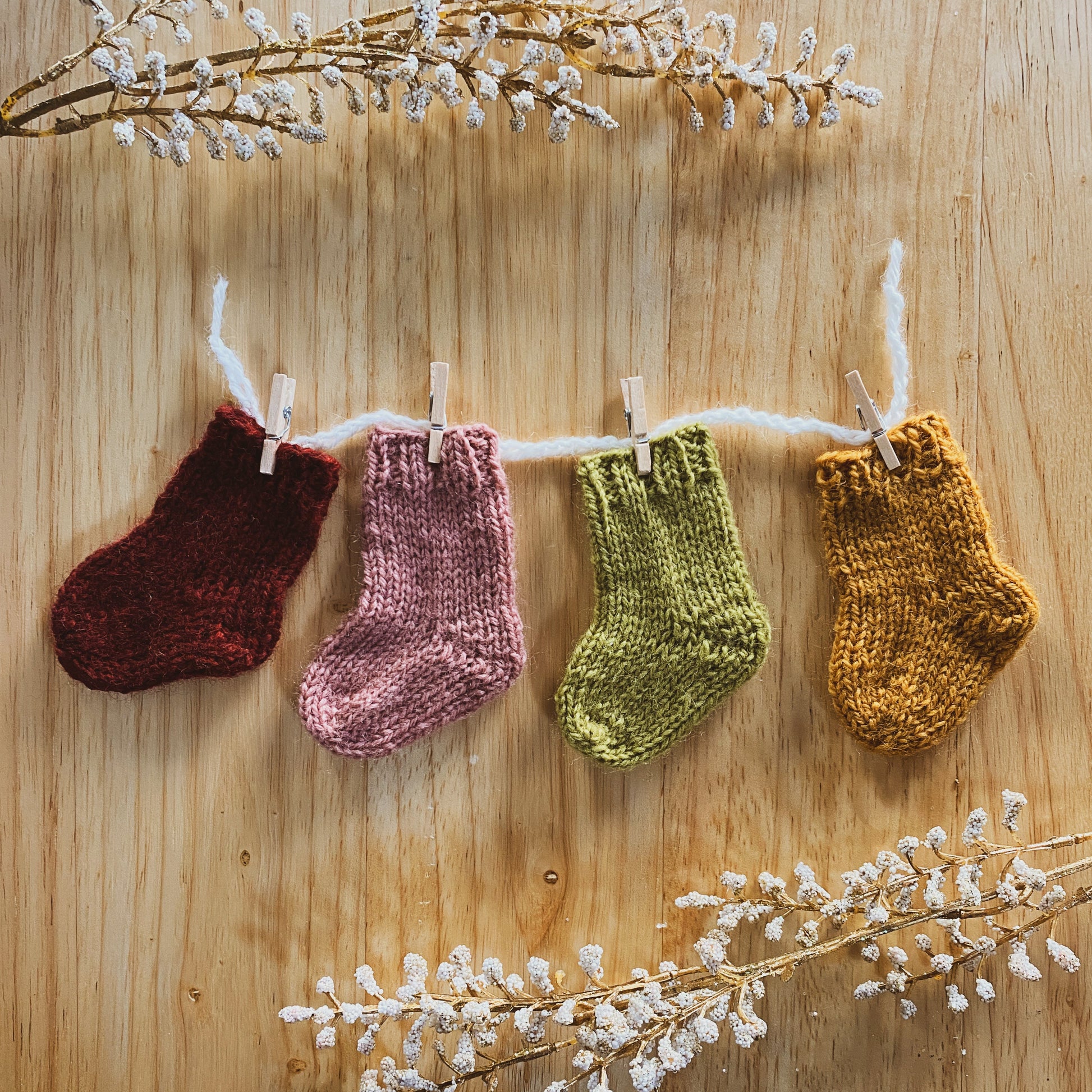 4 mini knitted stockings on a wooden surface