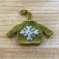 mini green knitted sweater ornament with a white snowflake embroidered on the front