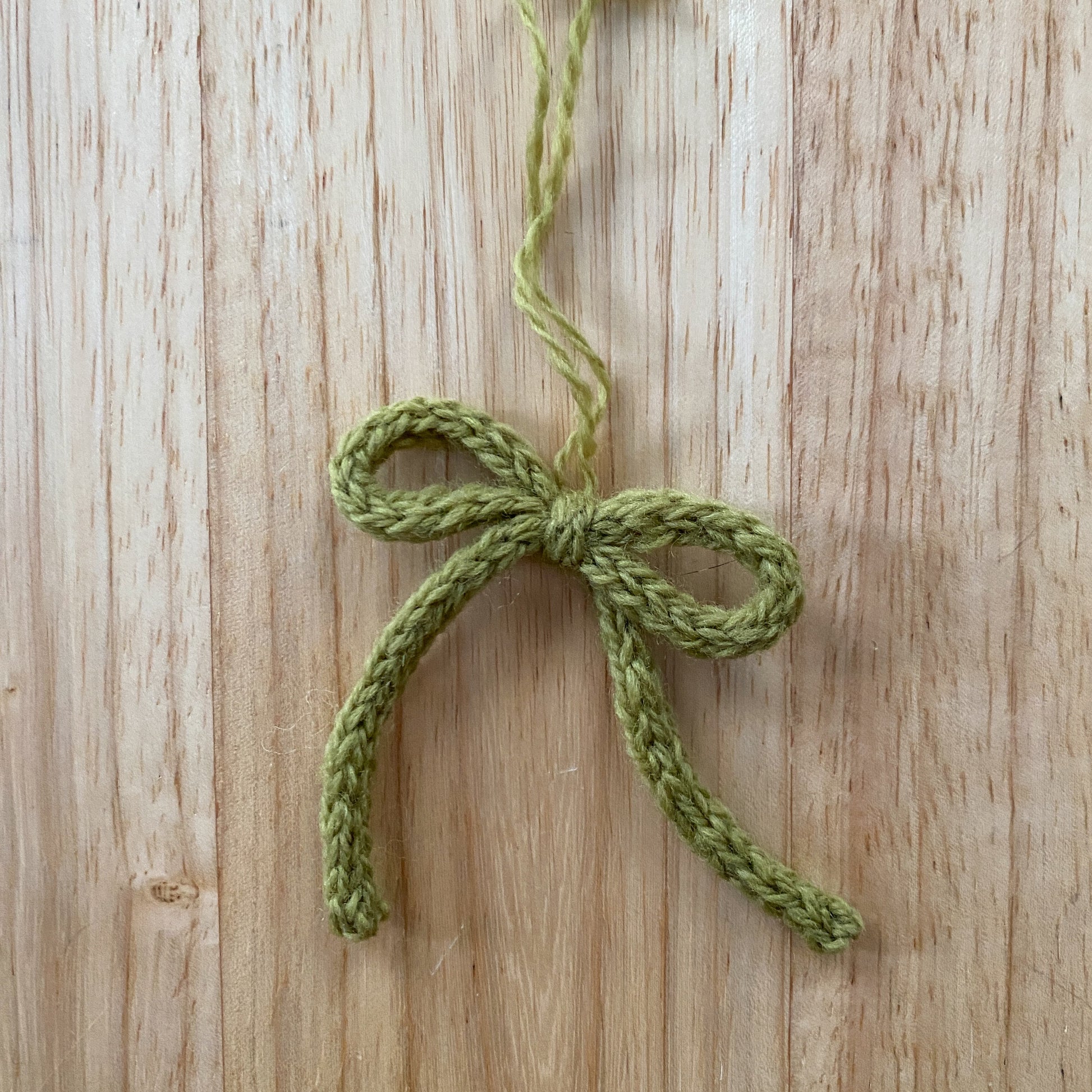 Green knitted bow on a wooden surface