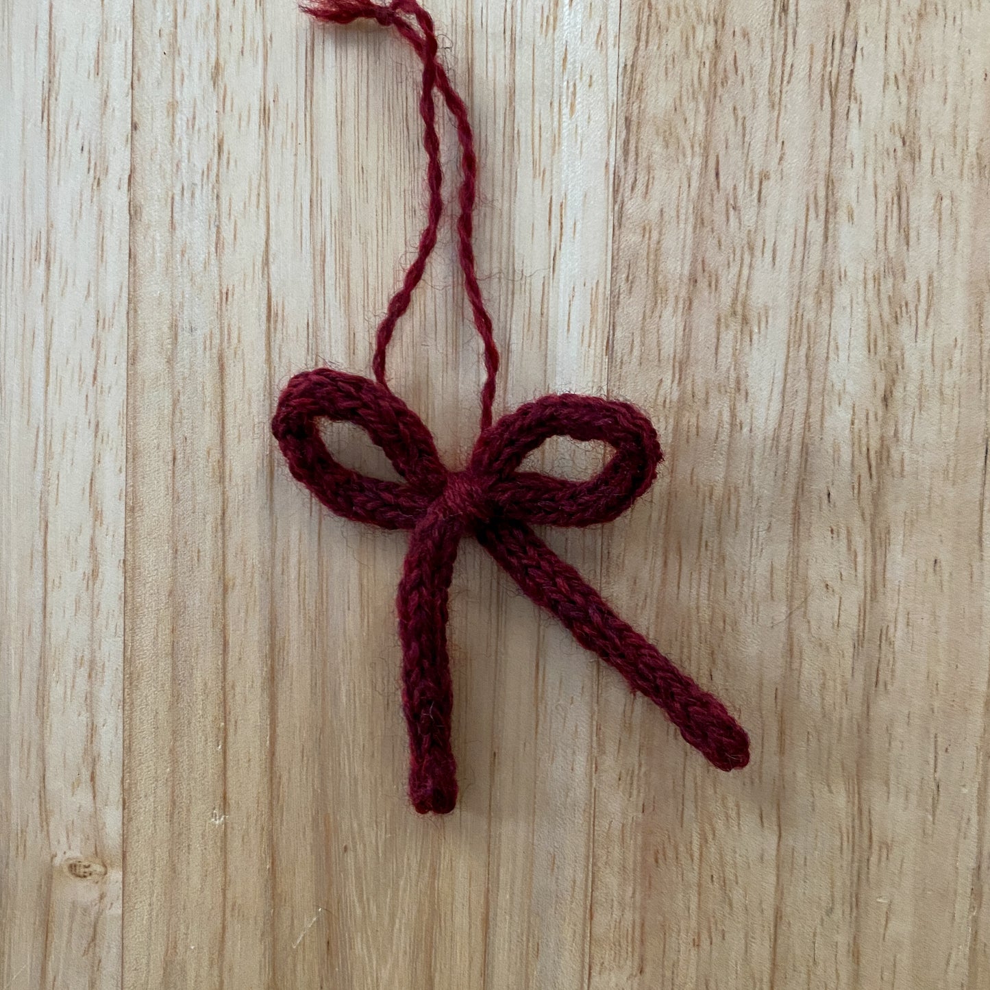 Knitted red bow on a wooden surface