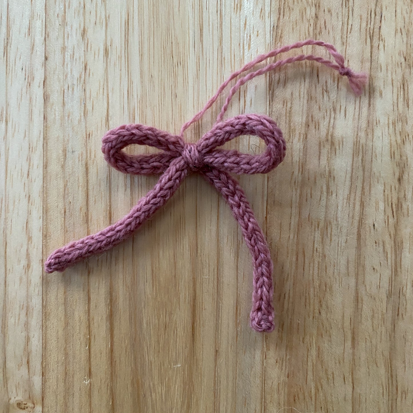 Pink knitted bow on a wooden surface