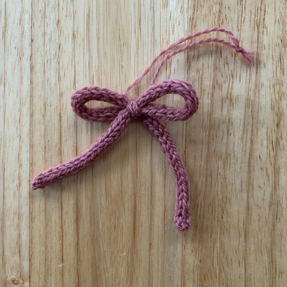 Pink knitted bow on a wooden surface