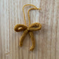 Knitted yellow bow ornament on a wooden surface