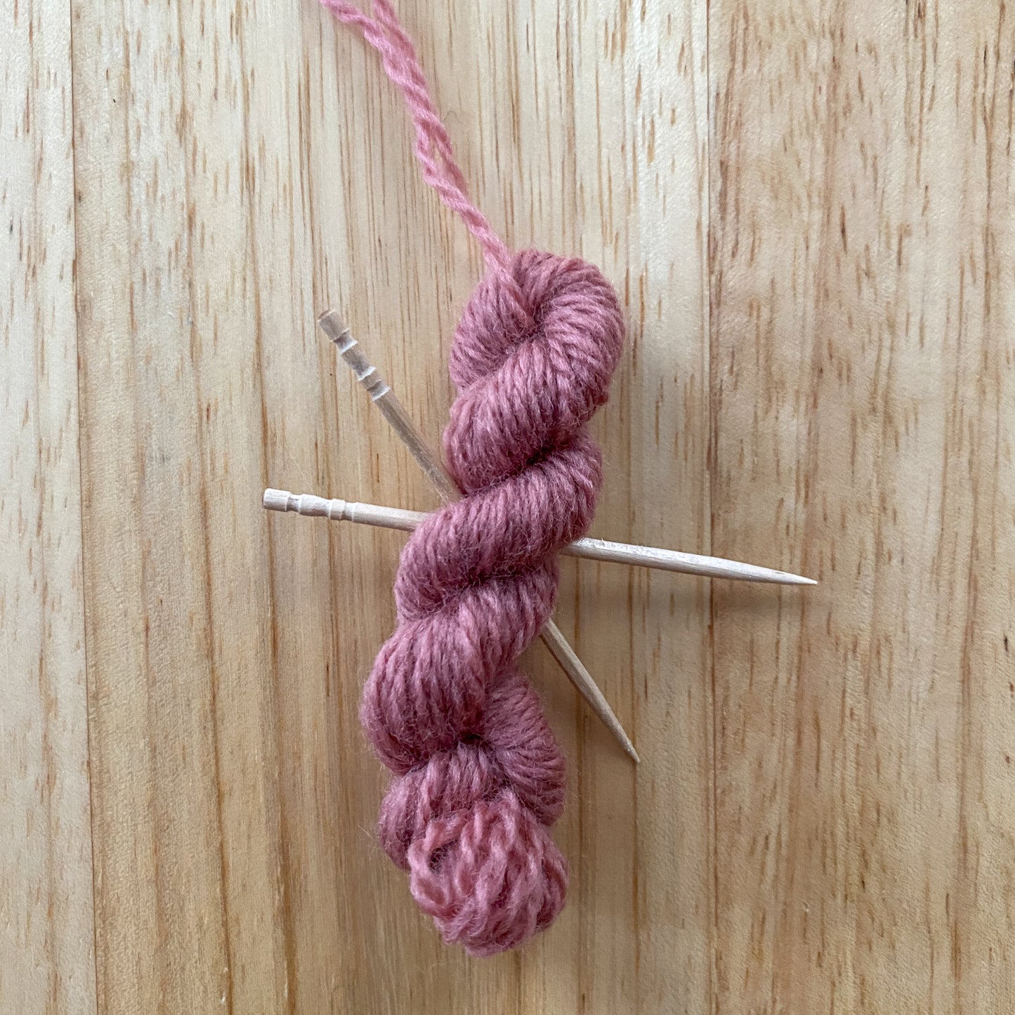 mini yarn skein ornament with toothpick knitting needles in pink