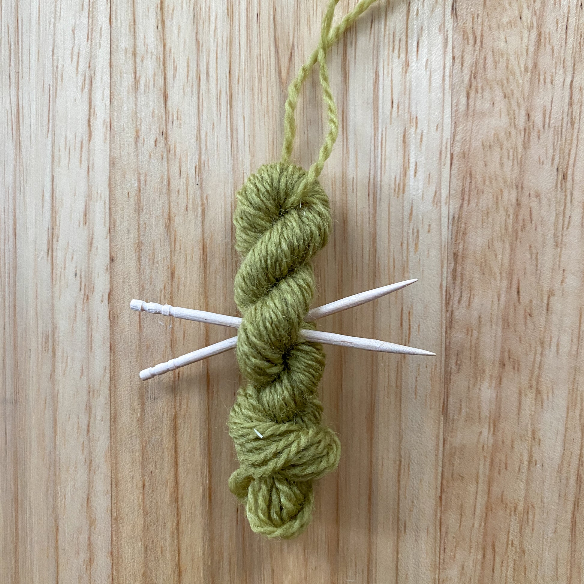 mini yarn skein ornament with toothpick knitting needles in lime green