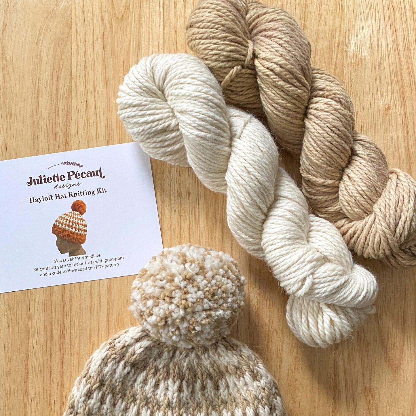 Knitted hat with yarn and a pattern sheet on a wooden surface