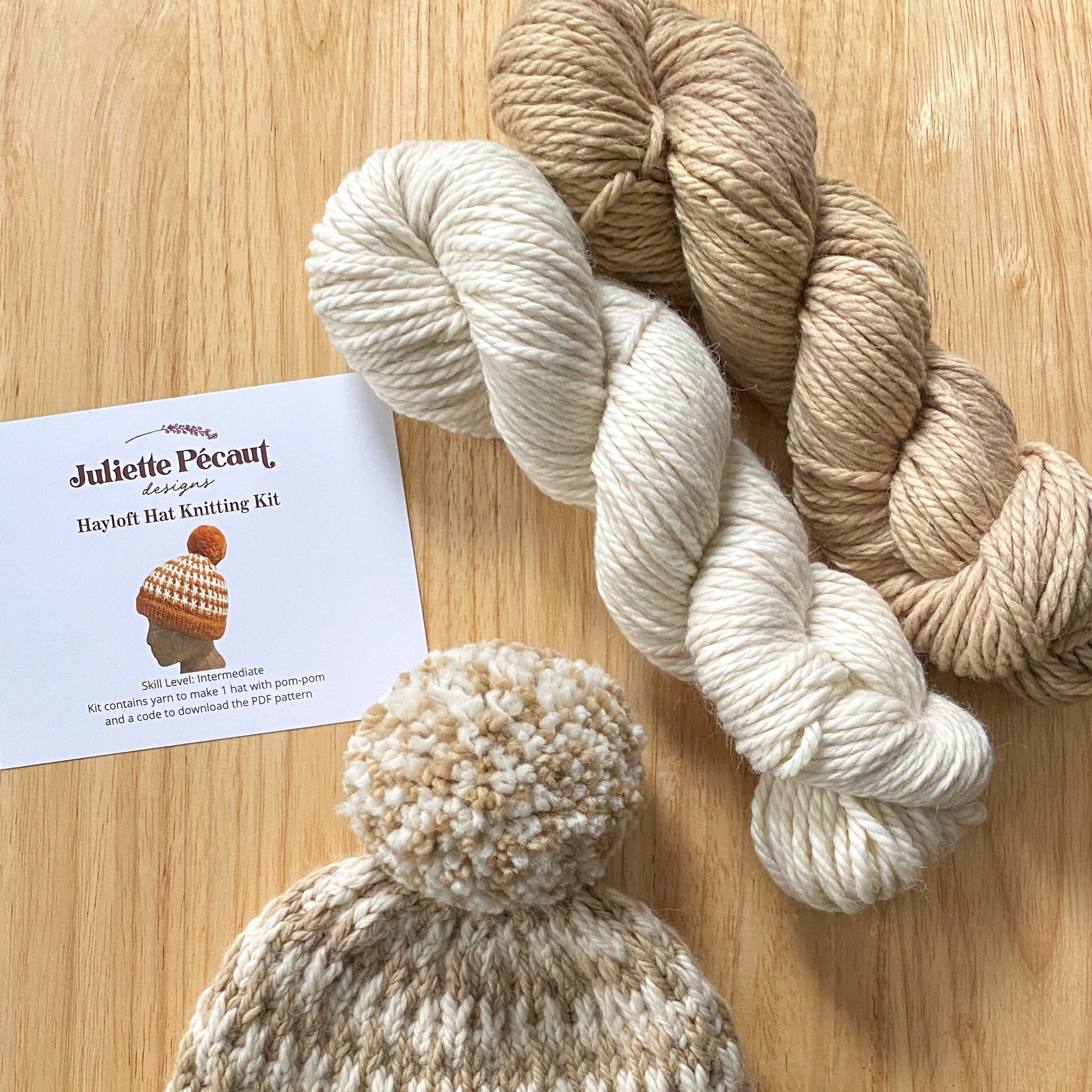 Knitted hat with yarn and a pattern sheet on a wooden surface