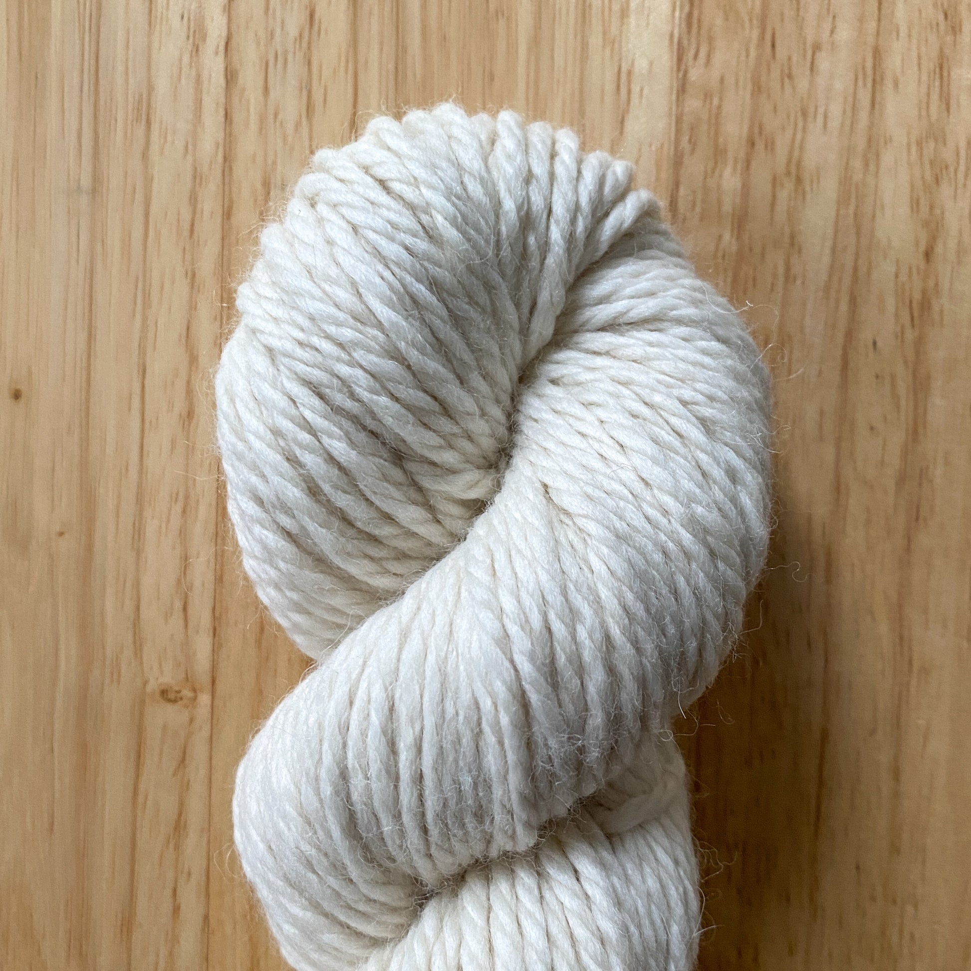 White skein of yarn on a wooden surface