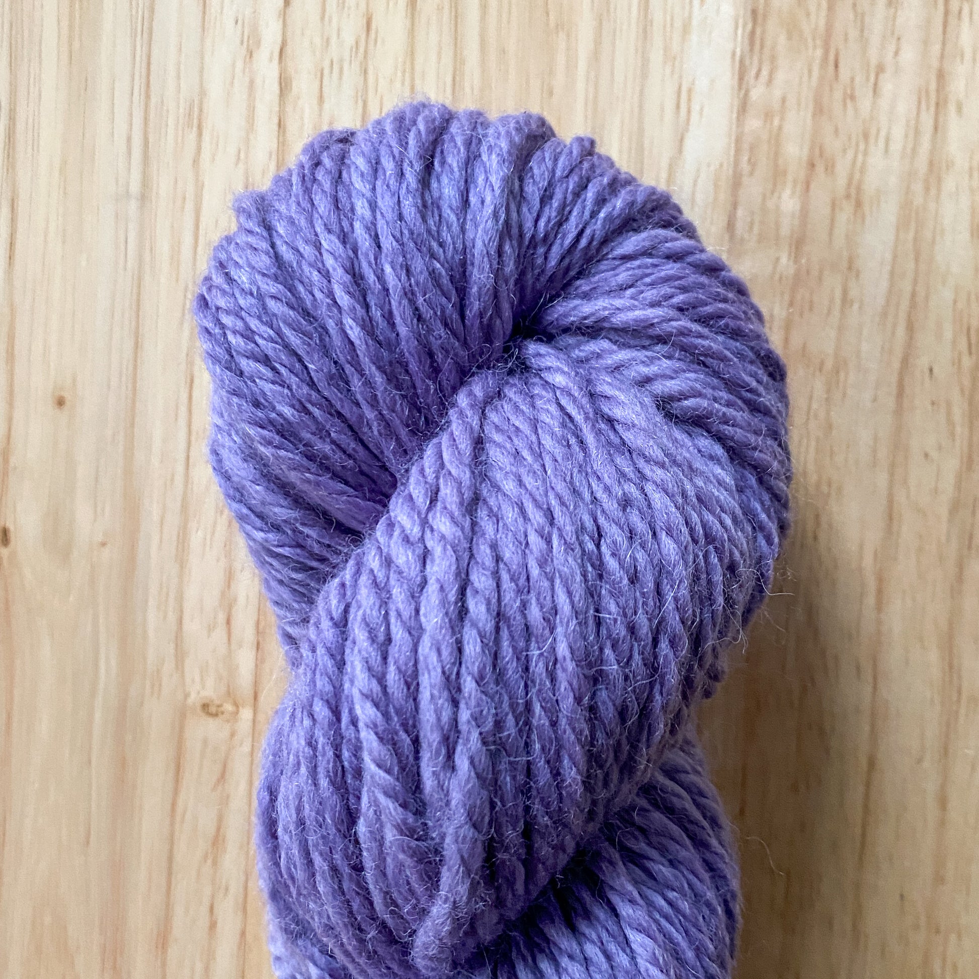 Purple skein of yarn on a wooden surface