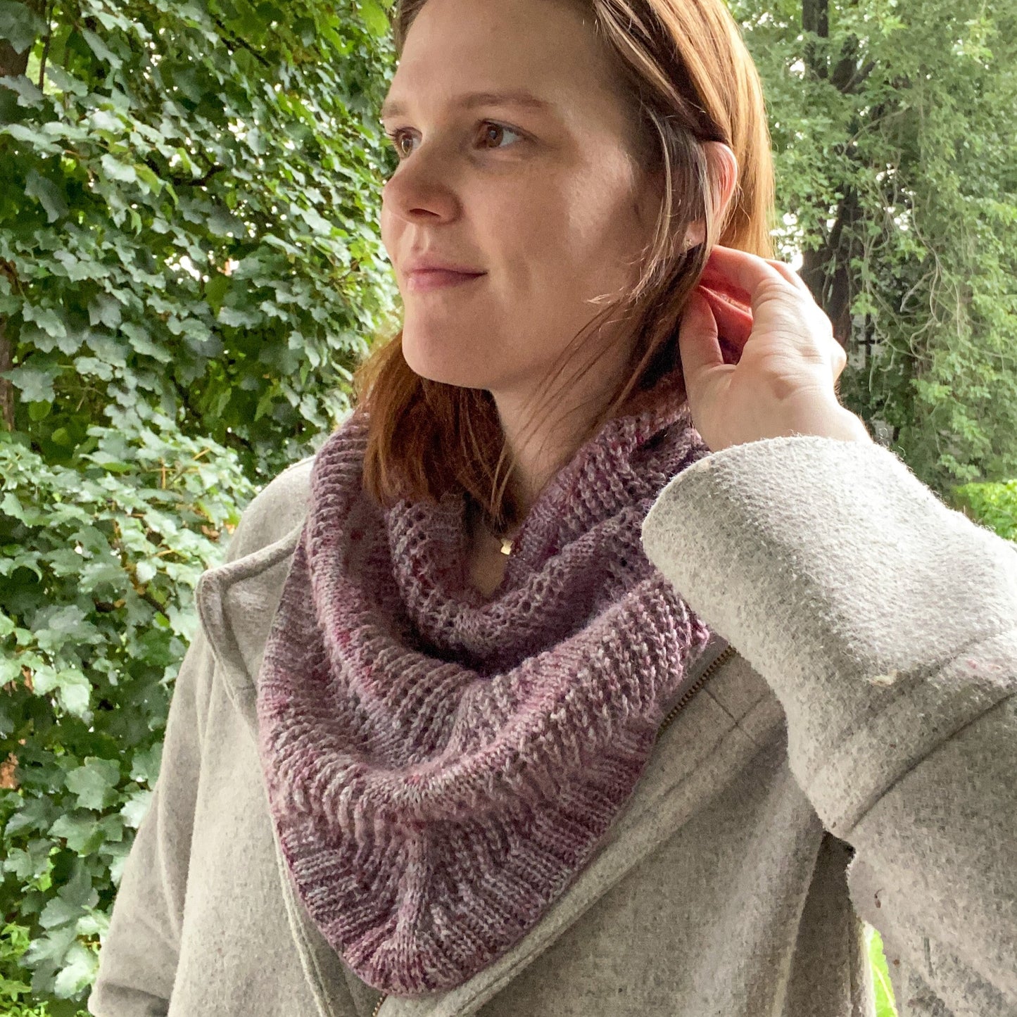jules, the designer, wearing a lace striped cowl with ribbing in a purple/pink yarn