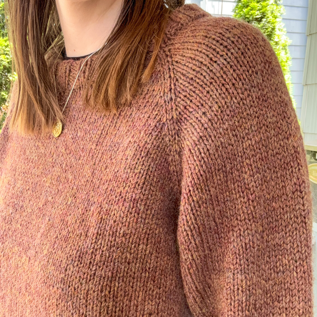 Person wearing a brown knitted sweater with a blurred background