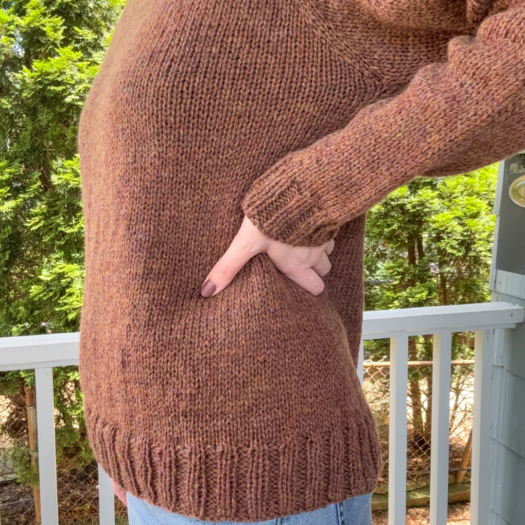 Person wearing a brown sweater with a blurred background