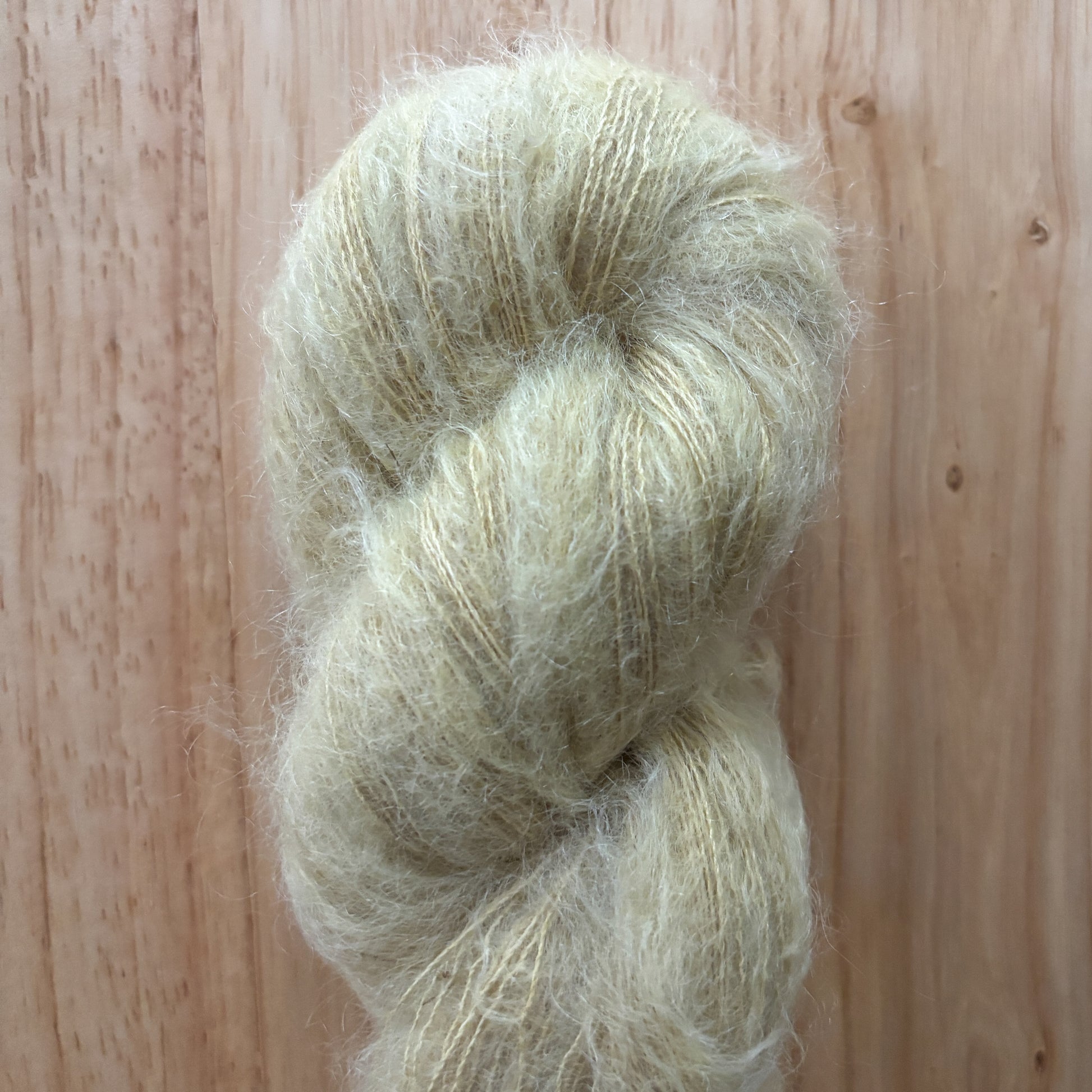 skein of fluffy light green yarn on a wood surface