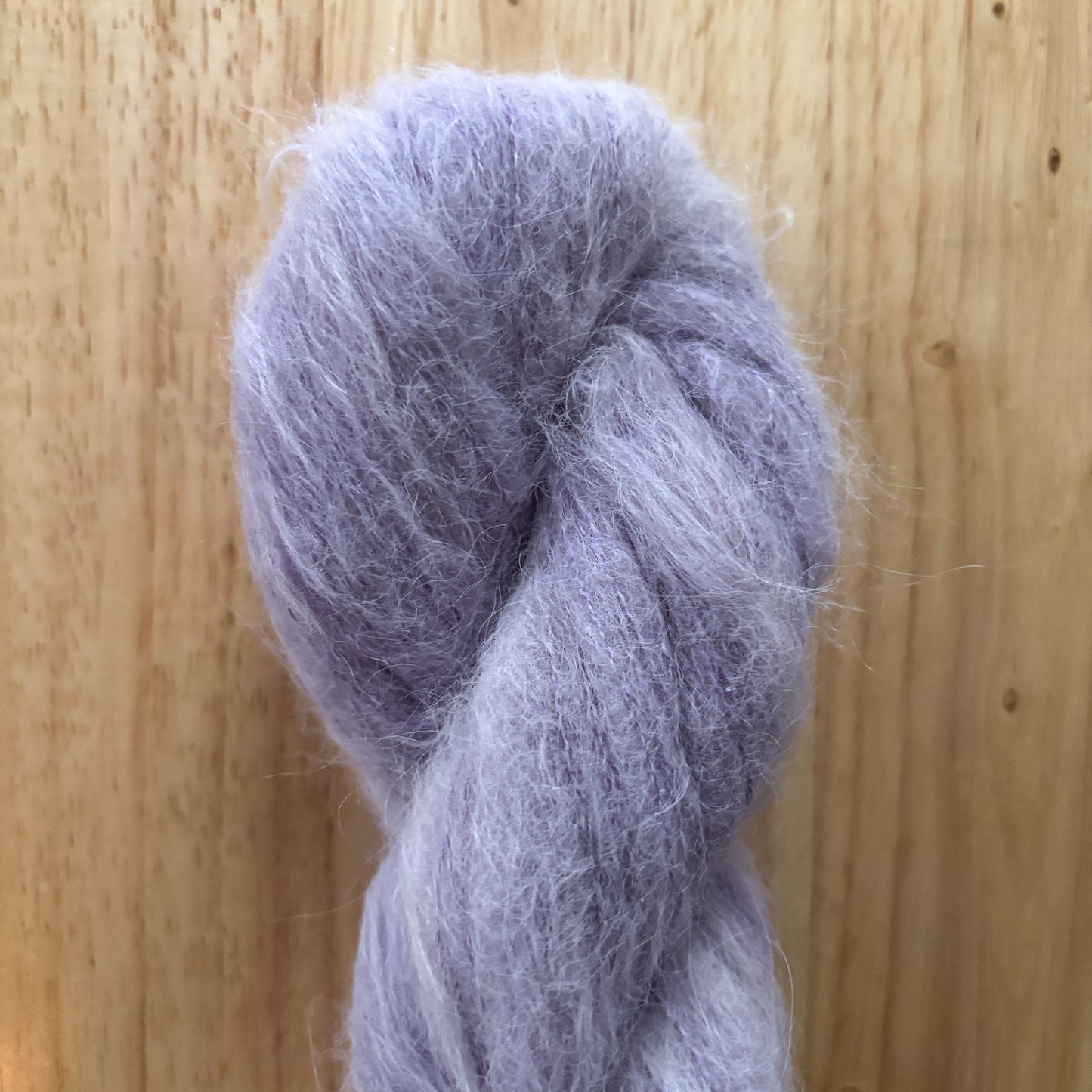 skein of fluffy purple yarn on a wood surface