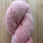 skein of fluffy pink yarn on a wood surface