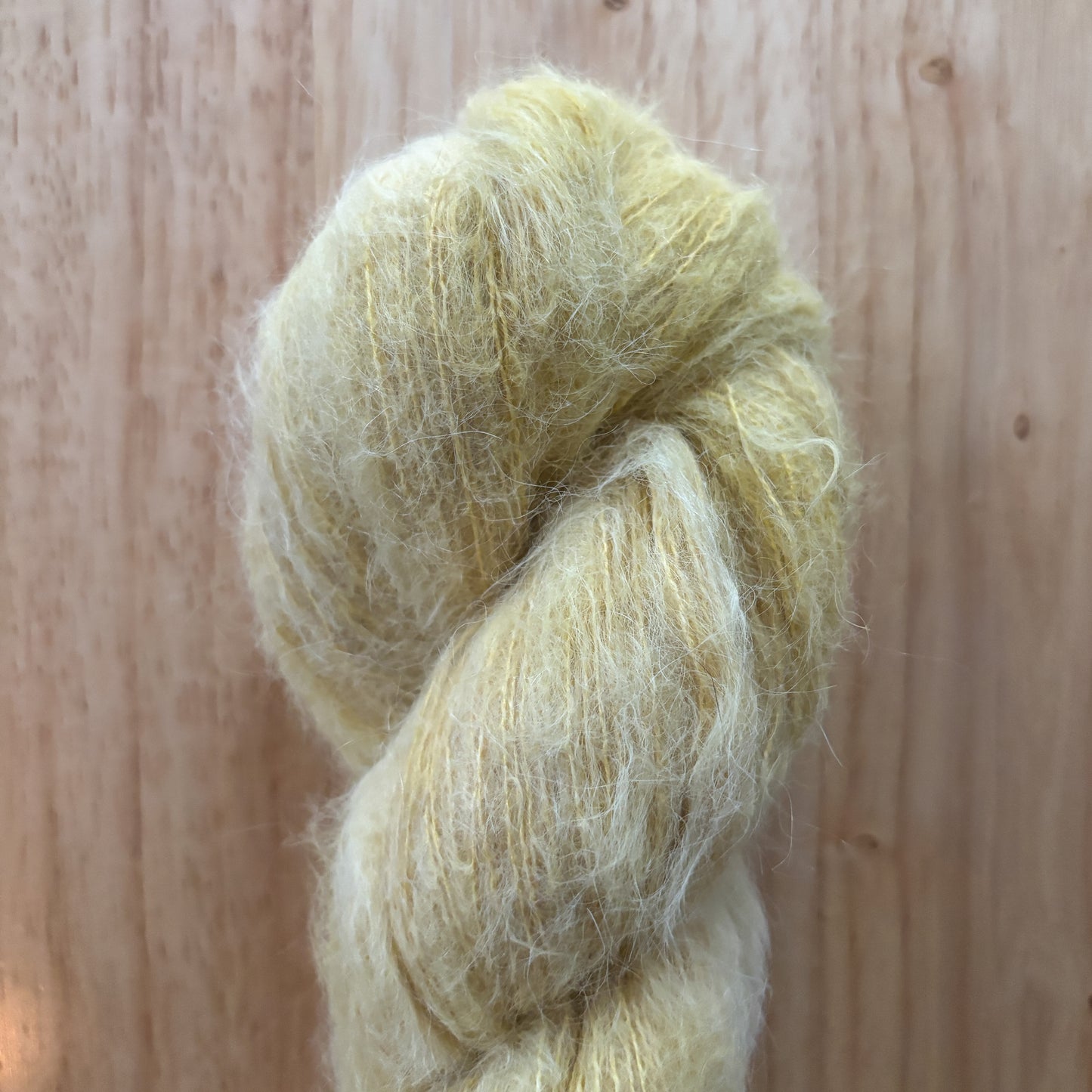 skein of fluffy pale yellow yarn on a wood surface