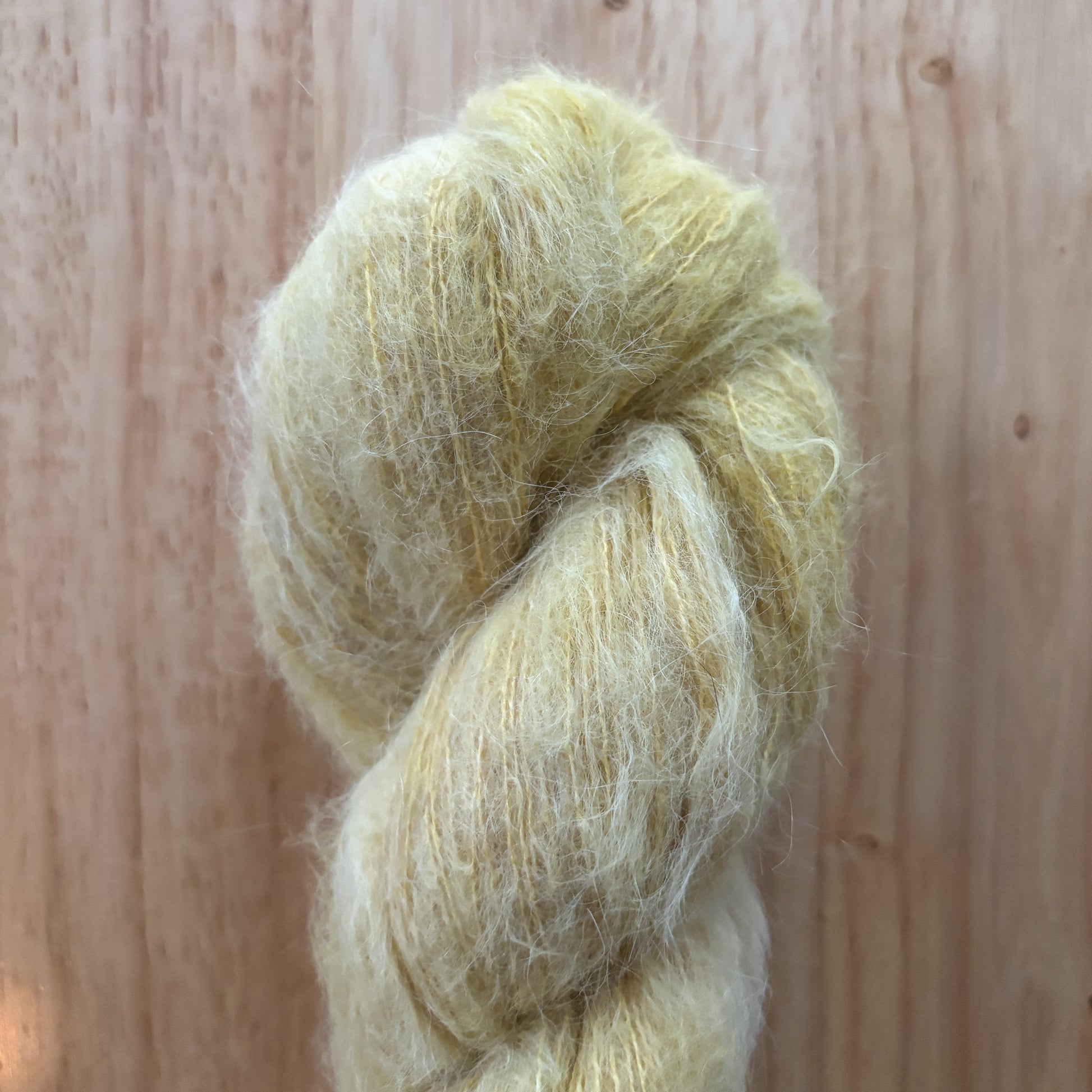 skein of fluffy pale yellow yarn on a wood surface